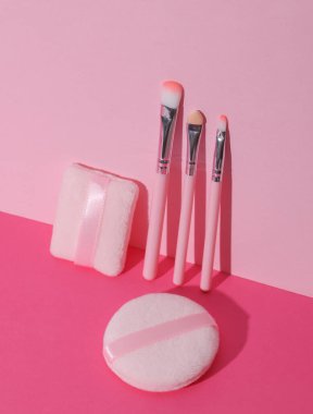 Makeup brushes and sponges on pink background