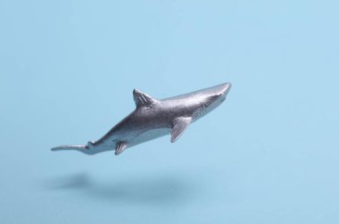 Oyuncak plastik köpekbalığı mavi arka planda yüzüyor