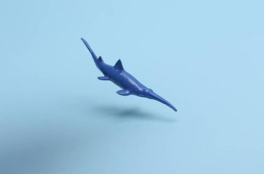 Oyuncak plastik köpekbalığı mavi arka planda yüzüyor