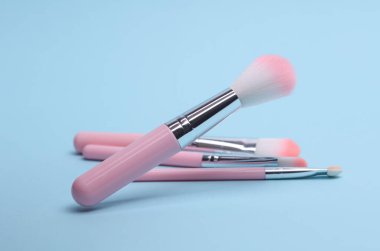 Mavi arkaplanda pembe makyaj fırçaları
