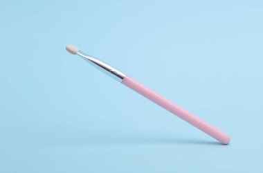Mavi arkaplanda pembe makyaj fırçası