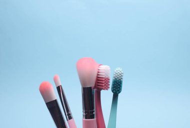 Mavi arka planda diş fırçası ve makyaj fırçası