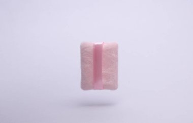 Gri arkaplanda yüzen pembe makyaj süngeri