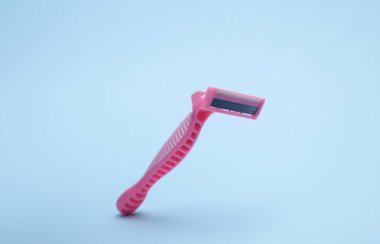 Mavi arkaplanda yüzen tek kullanımlık pembe jilet.