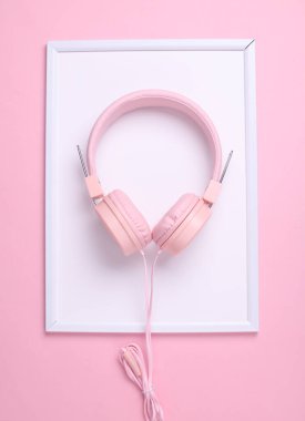 Pembe arka planda beyaz çerçeveli telli kulaklıklar. Üst görünüm