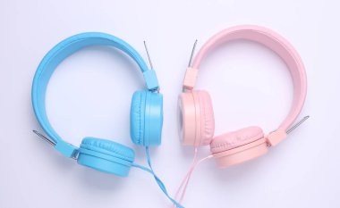 Beyaz arkaplanda pembe ve mavi Stereo kulaklıklar.