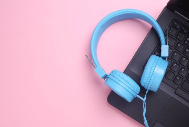 Pembe arka planda kablolu stereo kulaklıklı dizüstü bilgisayar. Üst görünüm