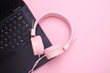 Pembe arka planda kablolu stereo kulaklıklı dizüstü bilgisayar. Üst görünüm