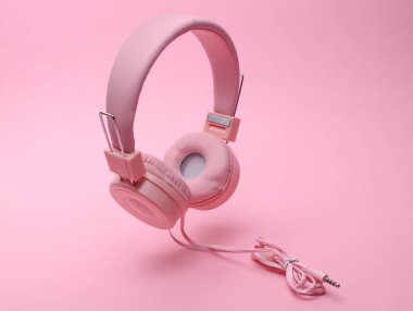 Pastel arka planda süzülen pembe müzik kulaklıkları.