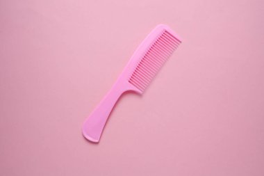 Pembe arka planda plastik tarak. Saç bakımı