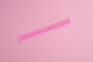 Pembe arka planda plastik tarak. Saç bakımı