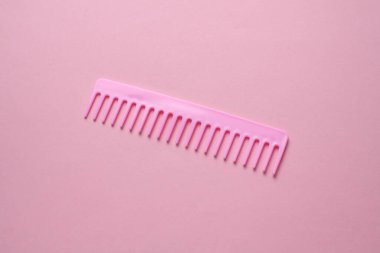 Pembe arka planda plastik tarak. Saç bakımı