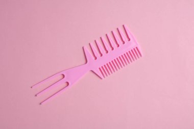 Pembe arka planda plastik tarak. Saç bakımı