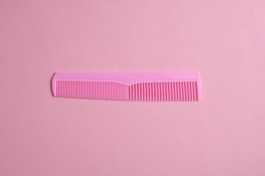 Pembe arka planda plastik tarak. Saç bakımı