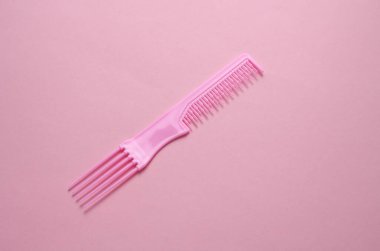 Pembe arka planda plastik tarak. Saç bakımı