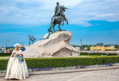 St.Petersburg, Russia -  July 5, 2013: A local woman in eighteenth-century costume in front of  the horseman statue of Peter the Great clipart