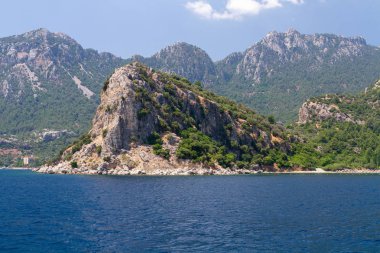 Ege Adaları'nın manzara manzarası. Denizin eşsiz tonları ve çam ağaçlarıyla kaplı kayalar. 