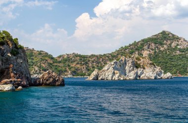 Ege Adaları'nın manzara manzarası. Denizin eşsiz tonları ve çam ağaçlarıyla kaplı kayalar. 