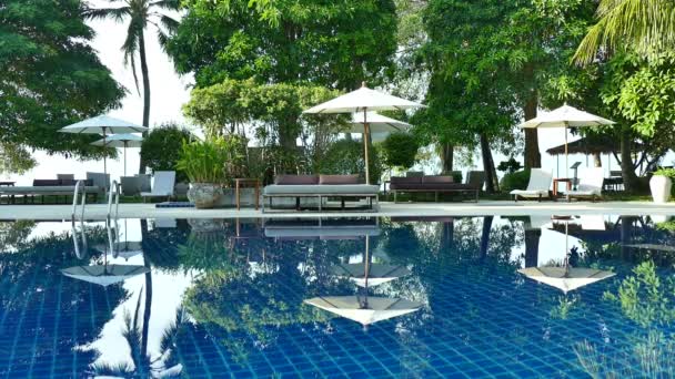 vue sur piscine, parasols et végétation tropicale luxuriante  