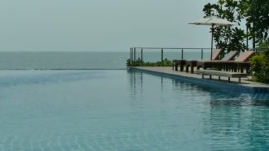 Yüzme Havuzu, plaj şemsiyeleri ve yemyeşil tropik bitki örtüsü 