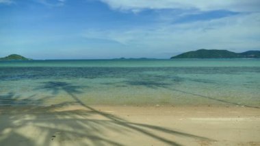 Deniz dalgaları, kumlu sahil ve mavi gökyüzü olan pitoresk bir marina.