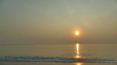 dalgalar deniz, kumsal ve dramatik gökyüzü günbatımı görünümünü