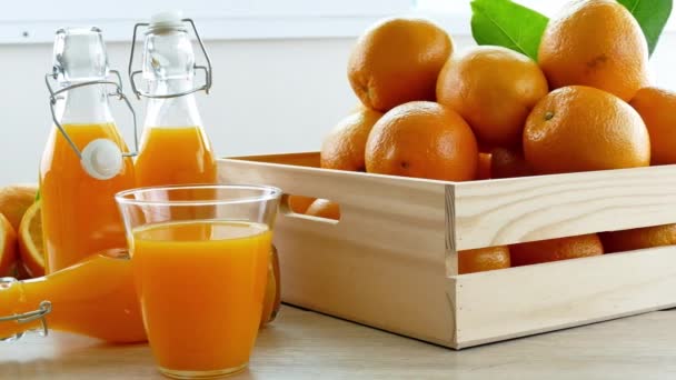 木の箱やジュースのガラスに新鮮なオレンジの山 — ストック動画