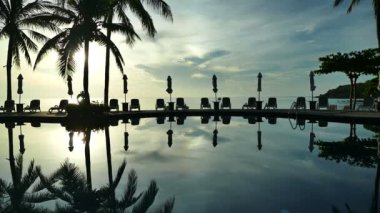 Yüzme Havuzu, plaj şemsiyeleri ve yemyeşil tropik bitki örtüsü 