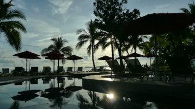 Yüzme Havuzu, plaj şemsiyeleri ve yemyeşil tropik bitki örtüsü 