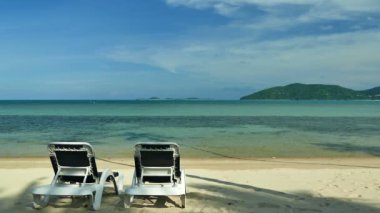 mavi okyanus dalgaları ile kumlu plajda şezlong