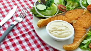 Soslu ızgara somon bifteği ve beyaz tabakta sebze. 