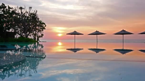 parasols et coucher de soleil sur la mer et la piscine
