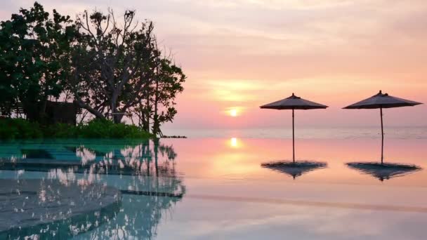 parasols et coucher de soleil sur la mer et la piscine