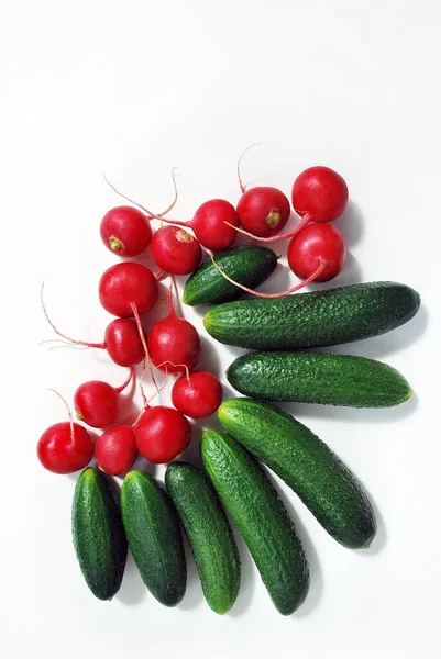 Green cucumbers and red radish on a white background close-up.