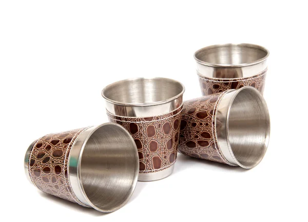 Metal flask trimmed leather and metallic sturdy shot glasses on a white background