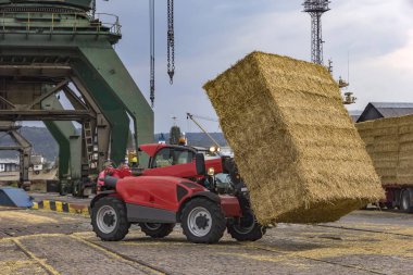  Telescopic handler unloading bales from truck. Day view. Work in a port clipart