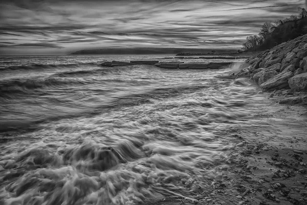 Black and white sea sunset. Beauty sea beach with motion blur water and waves flowing out.
