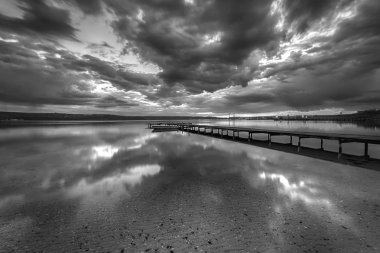 Bulutlar yansıması ile çarpıcı siyah beyaz uzun pozlama deniz manzarası.