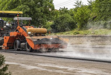 Asphalt paver machine makes a new road and repairing works. A paver finisher, asphalt finisher or paving machine placing a layer of asphalt. Repaving. clipart