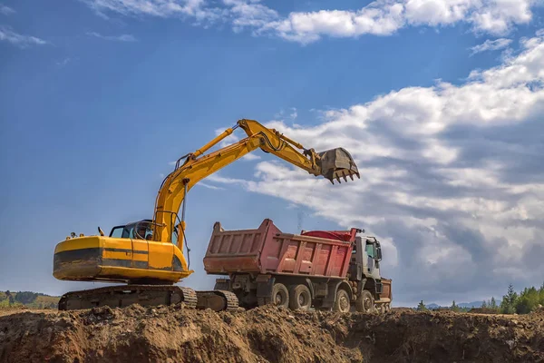 在施工现场工作的黄色挖掘机和空倾卸卡车 — 图库照片