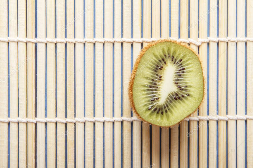 Ripe organic kiwi fruits on bamboo mat. Copy space. Chinese and japanese food concept. Top view.