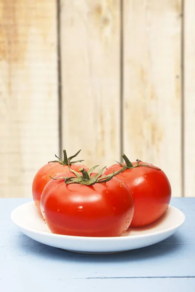 Fresh ripe tomatoes on wooden table and on background of wooden wall. Copy space. Organic vegetables for healthy breakfast or dinner.