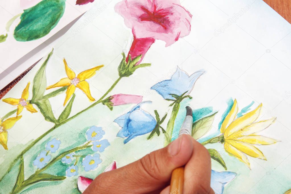 Girl draws beautiful wildflowers on white paper.