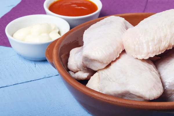 Fresh chicken wings of domestic bird in ceramic dishes for cooking a dietary dish. Space for design or text.