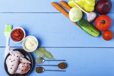 Tavuk kanatları, mayonez ve domates ahşap bir masa yapıştırın. Garnitür için taze organik sebze. Üstten görünüm. Kopya alanı.