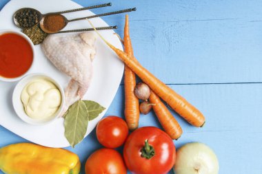 Diyet garnitür ve çiğ tavuk kanatları beyaz plaka üzerinde rustik bahçesinden taze organik sebze. Kopya alanı ile ahşap masa üzerinde üstten görünüm