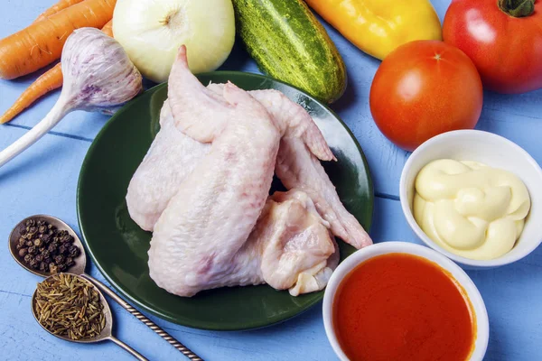 Et yemekleri yemek pişirmek için çiğ tavuk kanatları. Taze mayonez, domates sosu ve garnitür için rustik bahçesinden organik sebze. Sağlıklı gıda. Üstten görünüm.