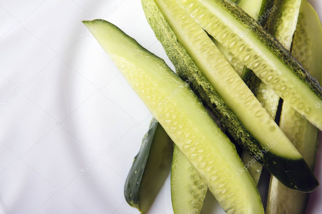 Sliced organic cucumbers on white plate with space for text or copy space. Top view.