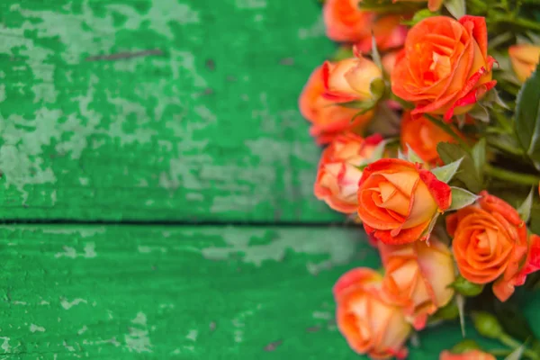 Orange roses on vintage wooden geen background. Soft focus.