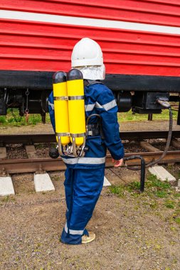 İtfaiye treninin yanında koruyucu üniforma giyen itfaiyeci.